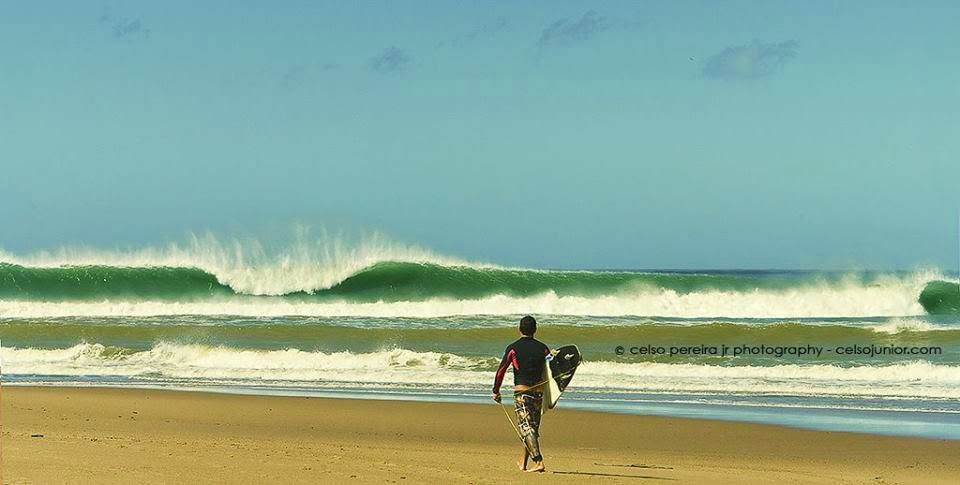 Esquerda longa e alinhada quebrando ao longo da praia deserta de Regência, com um surfista sozinho na areia